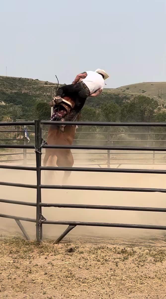 Bronc riding in a dusty arena